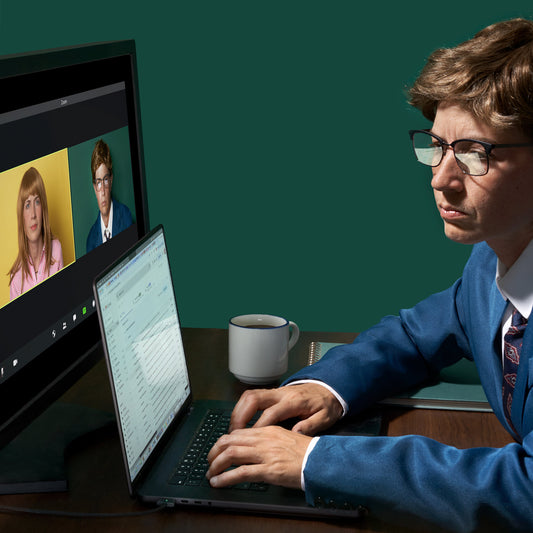 A person sitting at a desk with a laptop and a clock in the background