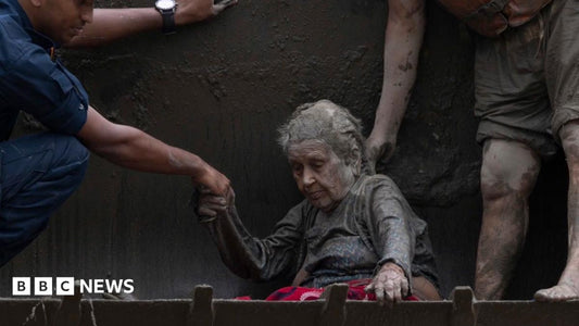 Excavator arm extending over floodwaters to lift a rescued elderly woman in Nepal