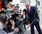 President Trump at a White House podium pointing to a list of media outlets labeled as banned