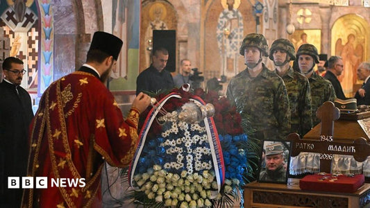 Crowd of mourners gathered outside the Serbian parliament for Ratko Mladić's funeral, holding Serbian flags.