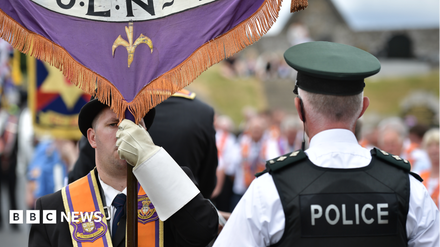 Police officers lining the route of an Orange Order parade in Belfast during a restricted march.