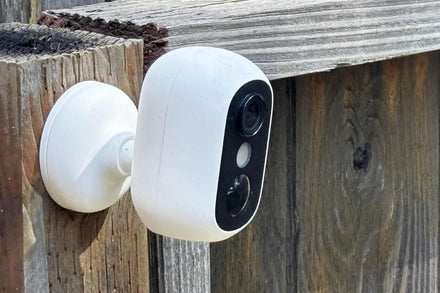 A person installing a security camera on their front porch