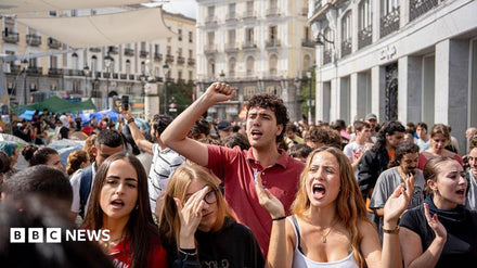 Protesters holding signs outside a Madrid apartment building demanding an end to evictions after an elderly woman's removal.