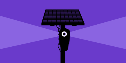 A city intersection with an automated license‑plate reader camera mounted on a traffic light pole.
