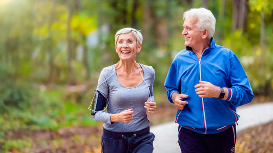 Couple walking hand‑in‑hand along a park trail at sunset, illustrating shared low‑intensity exercise.