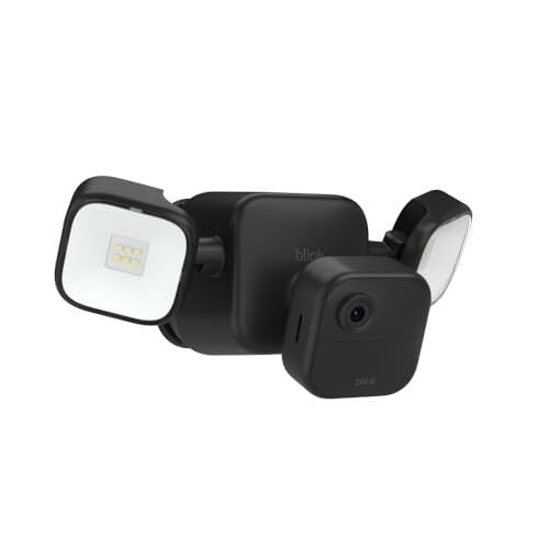 Blink Outdoor Floodlight Camera mounted on a backyard wall showing its battery compartment and floodlight lens.