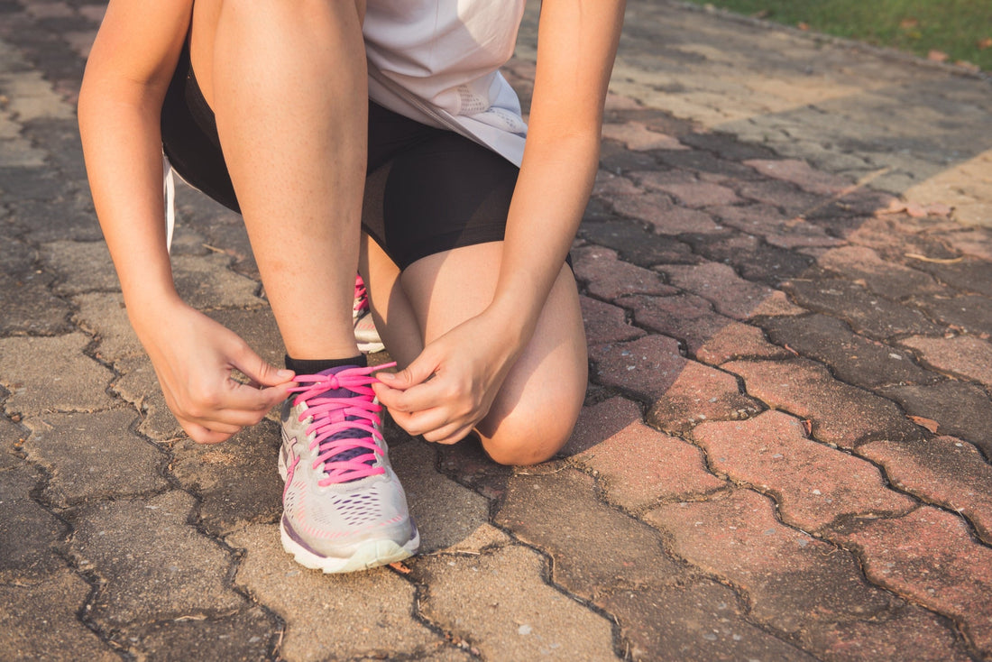 Tying shoelaces during an outdoor run, emphasizing readiness and safety.
