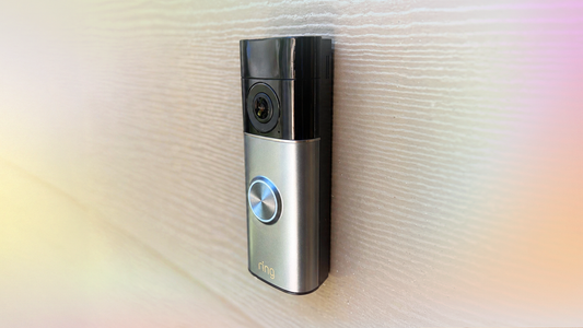 Close-up of a modern video doorbell mounted on a front door, showing its camera lens and motion sensor.