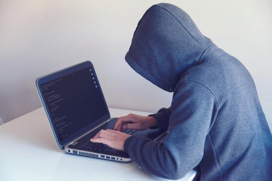 Person in hoodie typing on laptop, representing digital file security and protection strategies.