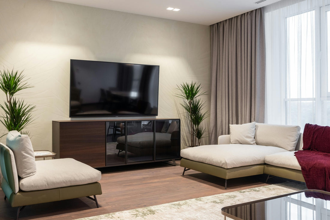 Modern hotel room interior with large TV, comfortable sofas, and green plants, emphasizing staying safe.