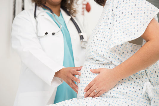 A pregnant woman holding a baby block with a dollar sign on it